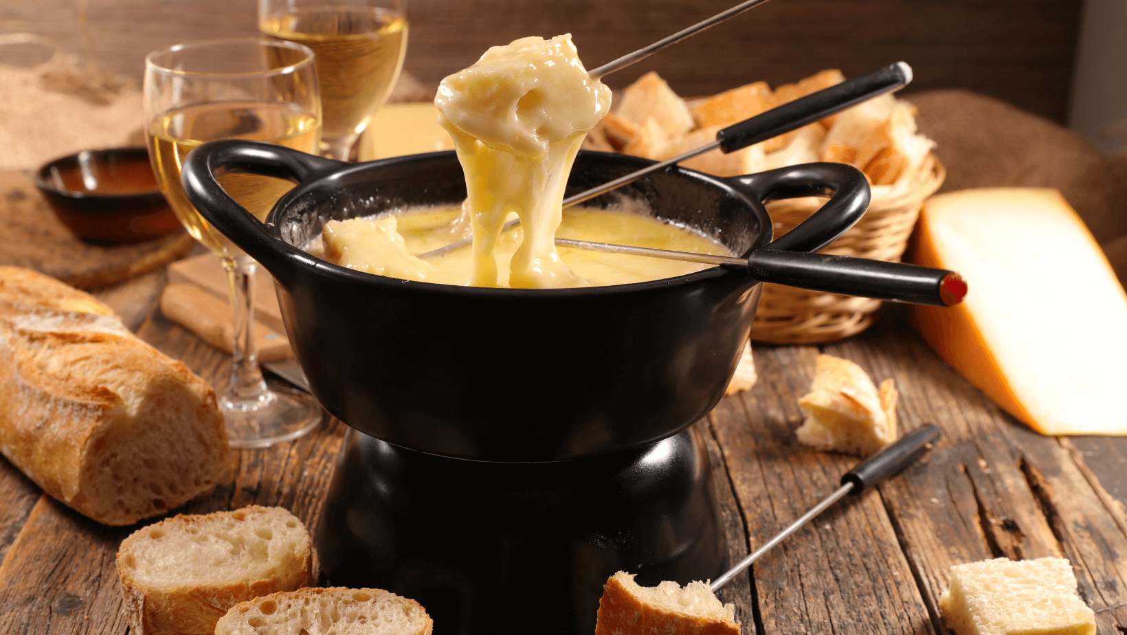 Fondue Cheese (melted cheese) in the traditional Swiss style, in a big pot with utensils for dipping of appetizers and finger foods