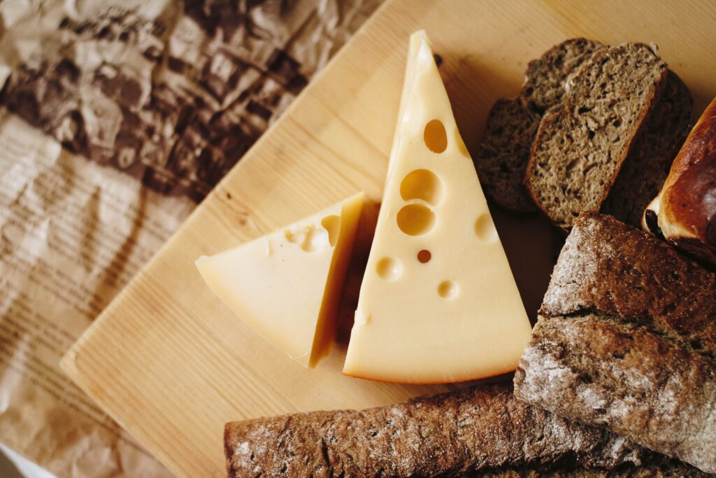 Wedges of cheese and rye bread, on a wooden tablescape.