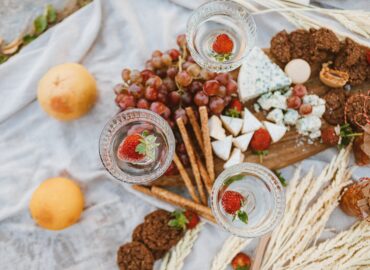 A festive cheese spread picnic including fruit, jam, snacks, and blue cheese.