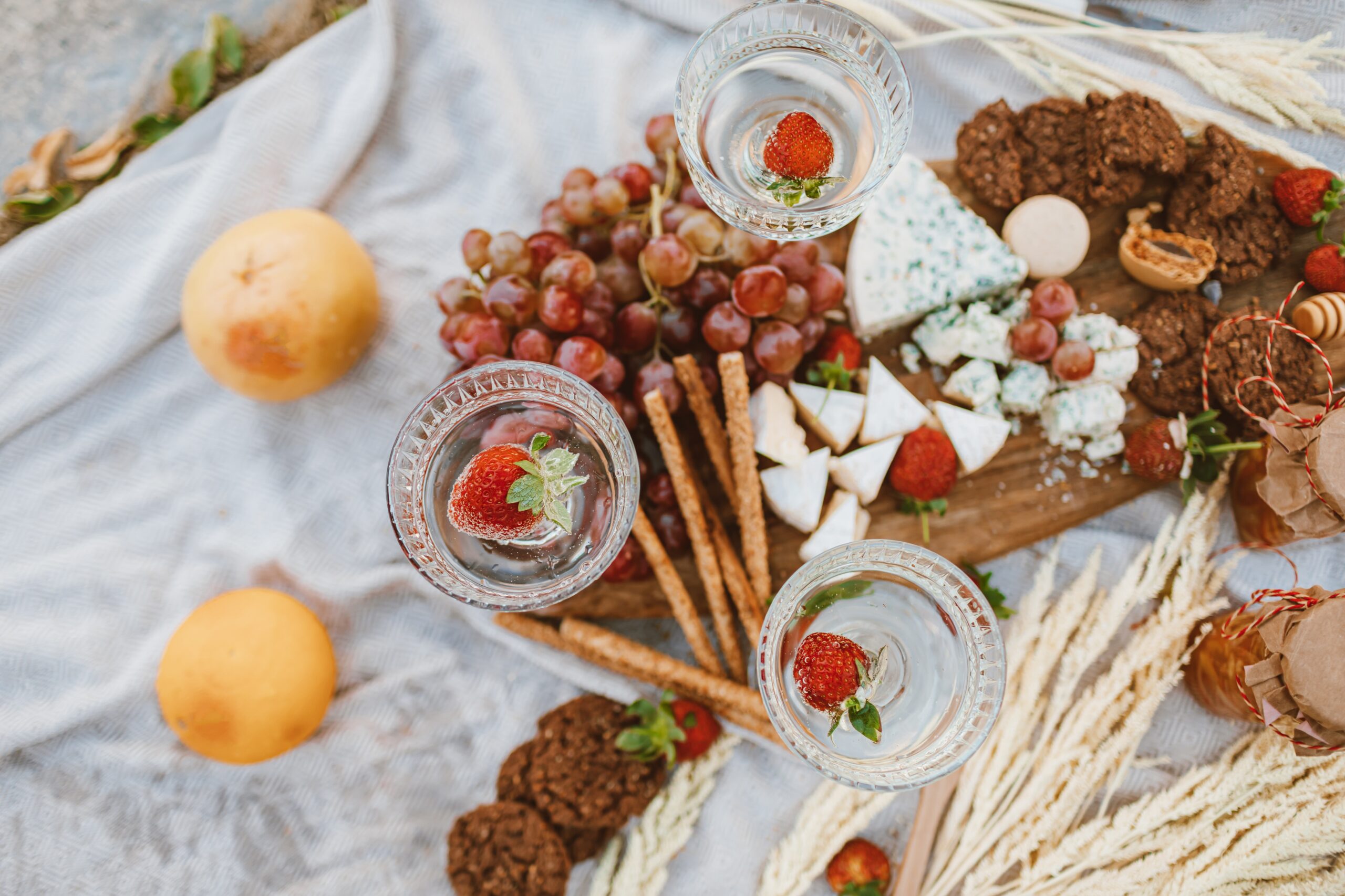 A festive cheese spread picnic including fruit, jam, snacks, and blue cheese.