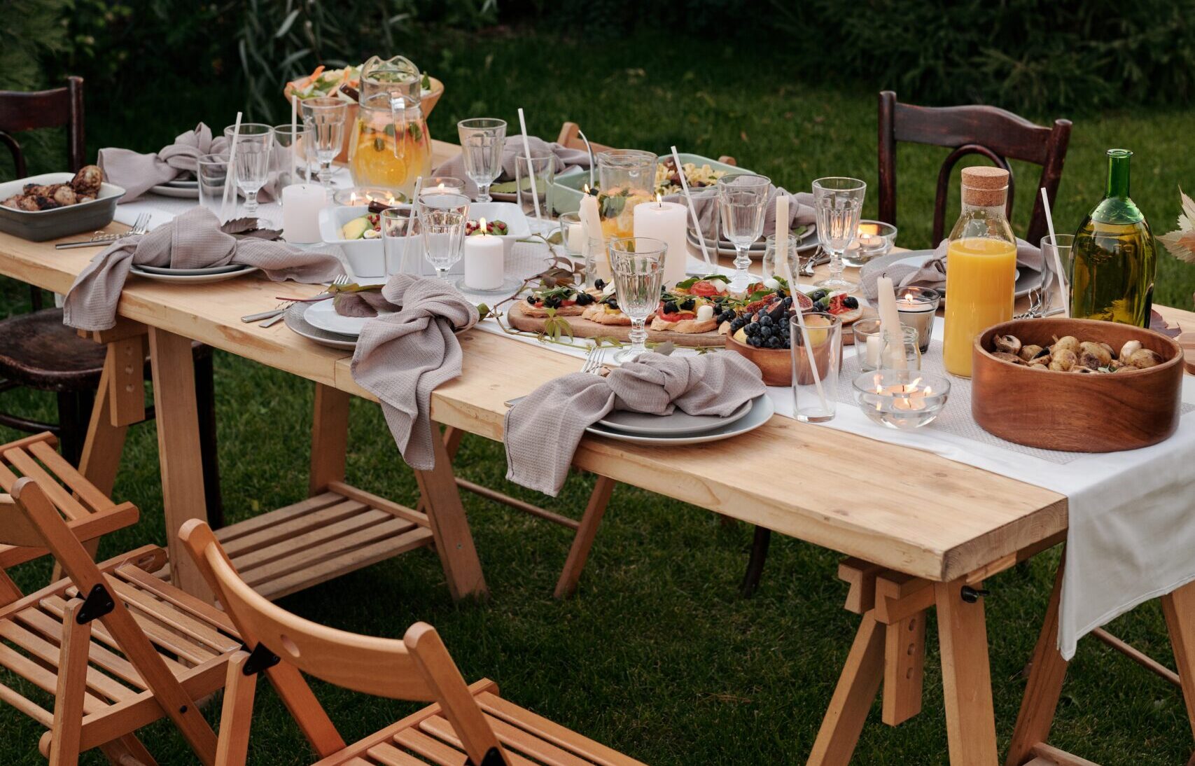 An outdoor picnic spread with cheese, fruits, and meat.